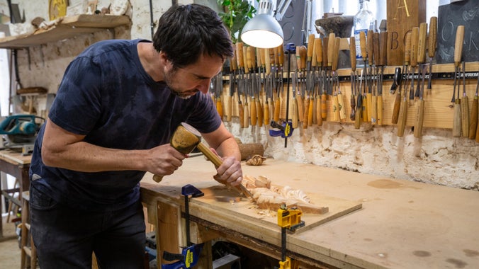 A craftsperson carving wood in his studio at the National Trust Heritage and Rural Skills Centre
